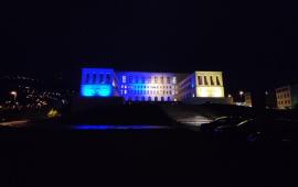the main facade of the University of Trieste illuminated blue and yellow, the colours of the Ukrainian flag
