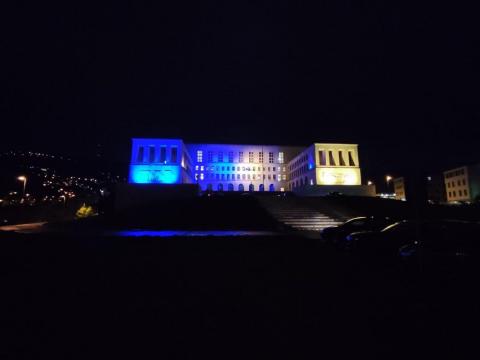 the main facade of the University of Trieste illuminated blue and yellow, the colours of the Ukrainian flag